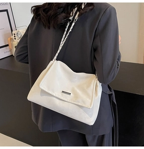 Detail of white leather tote bag featuring chain strap and silver logo on a model