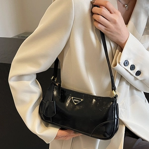 Minimalist black underarm bag in glossy oil wax leather with triangular metal logo plate