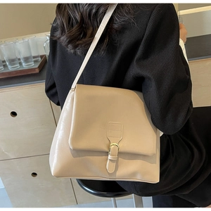 Side view of cream PU leather tote bag worn by a model in a minimalist warm setting