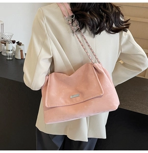Detailed view of pink suede chain shoulder bag worn over a beige suit for commuters