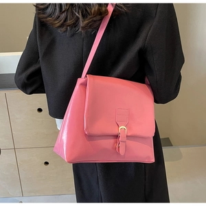 Back view of model wearing a pink faux leather crossbody tote with gold buckle detail