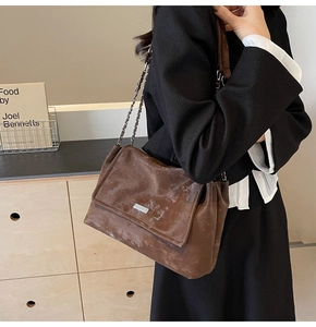 Detail of vintage brown crossbody tote bag with chain strap and metallic flap clasp