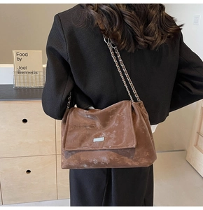 Detail of vintage brown leather tote bag with silver chain strap on black blazer