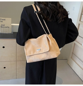 Detail of light beige suede tote bag with silver chain strap on black blazer