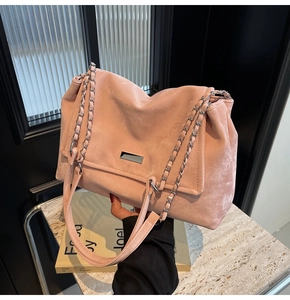 Detail of pink suede tote bag featuring silver chain strap and metal buckle hardware