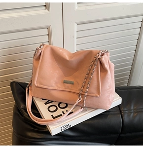 Detail of coral pink leather shoulder bag with chic chain strap and metal clasp