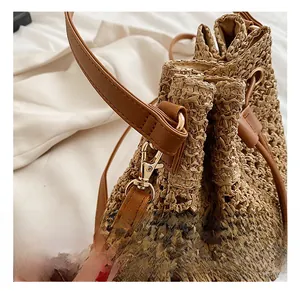 Close-up of golden metal hooks and brown leather straps on a woven straw bucket bag