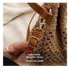 Close-up of adjustable brown leather shoulder strap with gold metal hooks on woven bag