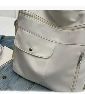 Detail of white nylon tote bag with functional magnetic flap and metal side zipper