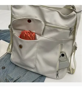 Detailed view of white minimalist shoulder bag with multiple functional storage pockets