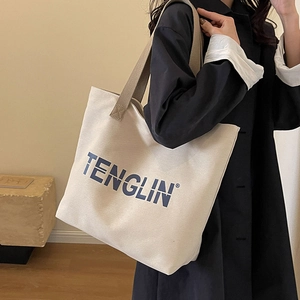 Large cream canvas tote bag with brown straps shown on shoulder for daily commute