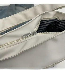 Detail of smooth metal zipper and blue striped lining on canvas tote bag