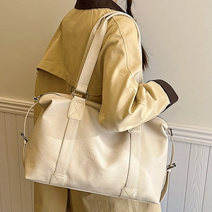 Grand sac cabas crème en cuir PU avec large bandoulière porté par un mannequin en trench