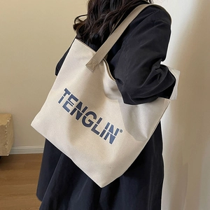 Minimalist off-white canvas tote bag with TENGLIN print shown from a side view on model
