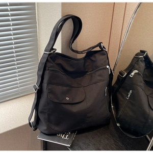 Close-up of black nylon tote bag with multi-pocket design and silver zippers for daily work
