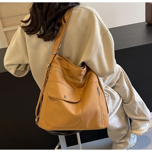 Detail of yellow canvas tote bag showing side zipper and adjustable metal buckle strap