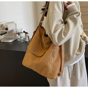 Detail of tan canvas crossbody bag with multiple zip pockets shown on a model