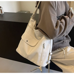 Detail of a beige canvas tote bag with multi-pocket design and adjustable wide strap