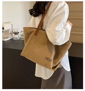 Detail of khaki tote bag featuring black TELN logo and brown leather shoulder straps
