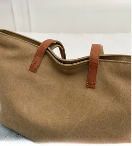 Close-up of khaki canvas tote bag showing durable texture and brown leather handle