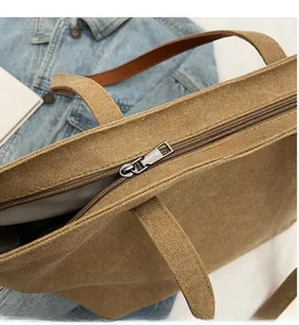 Detail of tan canvas tote bag showing smooth zipper closure and durable woven handle