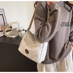 Detail of cream nylon tote bag with adjustable strap in a modern lifestyle setting