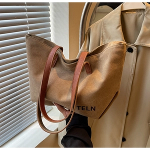 Detail of khaki canvas tote bag with brown leather handles and black TELN branding