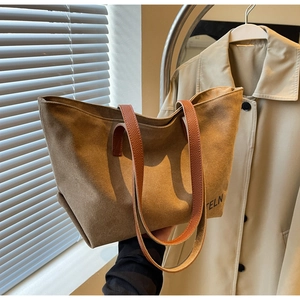 Detail of khaki canvas tote bag with brown leather handles and TELN logo print