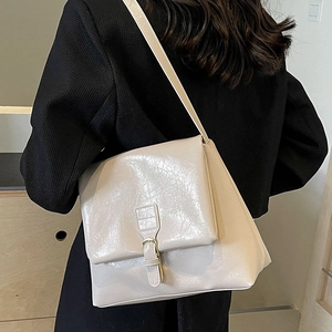 Minimalist beige tote bag with textured faux leather and flap cover shown on model