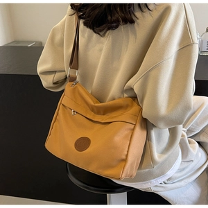 Detail of yellow nylon tote bag with logo patch and adjustable crossbody strap