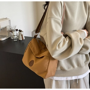 Detail view of mustard yellow nylon tote bag being worn to show size and crossbody style