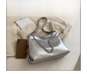 Detail of silver metallic tote bag with crinkled texture and sleek chain strap design