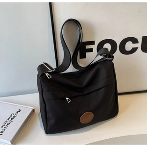 Detail of black nylon tote bag showing adjustable wide shoulder strap and metal hardware