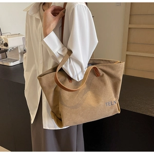 Close-up of a large khaki canvas tote bag with brown leather straps and TELN branding