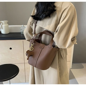 Detail of brown leather bucket bag with elephant charm and fashion trend embossing