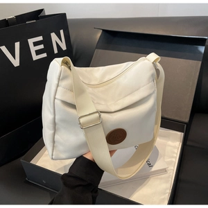 Detailed shot of a beige nylon crescent bag in premium packaging with adjustable strap