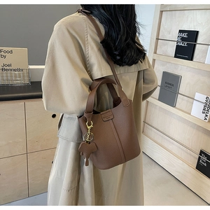 Detail of dark brown lychee leather bucket bag with cute elephant charm on a model