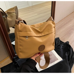 Detail of ginger nylon tote bag with wide strap and embossed leather patch logo
