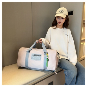 Close-up of pink oxford travel bag featuring a logo patch and a green smiley face charm