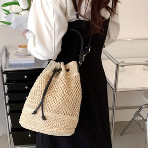 Large woven bucket beach bag with black drawstring and leather strap for summer vacation
