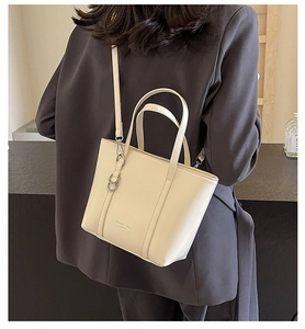 Detail of off-white leather tote bag with silver metal rings and detachable strap
