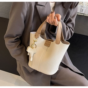 Close-up of ivory bucket bag with pebble leather texture and elephant charm