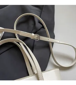 Detail of adjustable white leather shoulder strap with silver buckle on tote bag