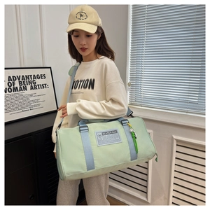 Close-up of mint green nylon travel bag featuring branding tag and blue carry straps