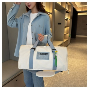 Detail of large white Oxford cloth travel bag with light blue straps and green smiley charm