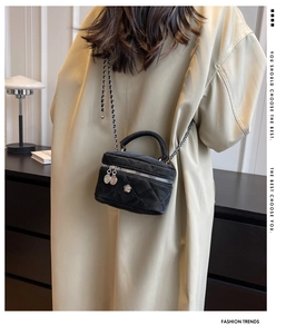 Détail du sac matelassé noir avec fleur de camélia argentée et bandoulière chaîne