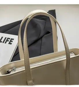 Detail of cream tote bag featuring sturdy top handles, neat stitching, and metal zipper