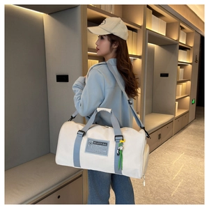 Detail of a large off-white travel bag with grey straps shown in a minimalist room