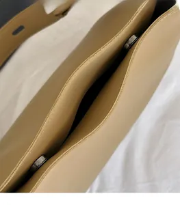 Detailed close-up of premium metal magnetic buckle on light khaki leather bucket bag