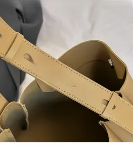 Detail view of the adjustable leather strap with metal stud buckle on the bucket bag